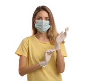 Young woman in protective face mask putting on medical gloves against white background