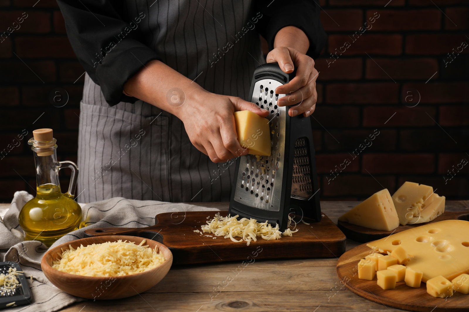 Photo of Woman grating cheese at wooden table, closeup