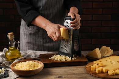 Woman grating cheese at wooden table, closeup