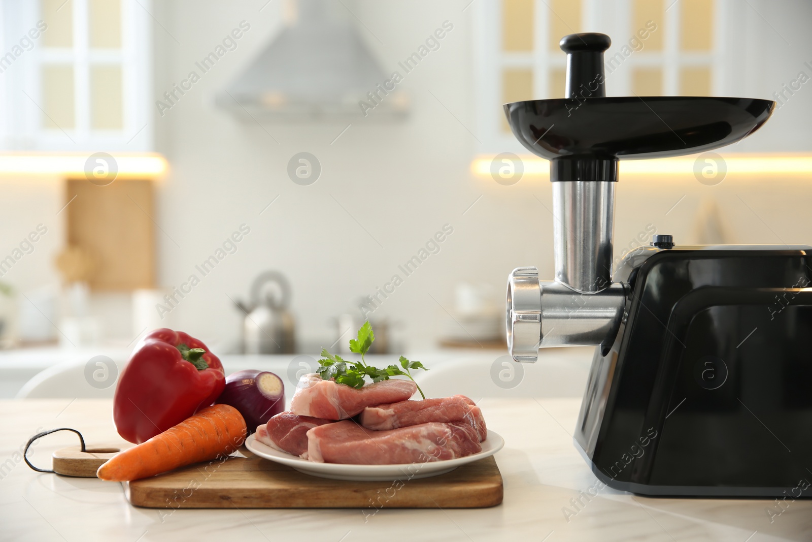 Photo of Modern meat grinder and products on white marble table in kitchen. Space for text