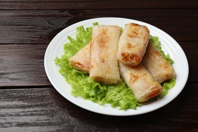 Photo of Delicious fried spring rolls on wooden table