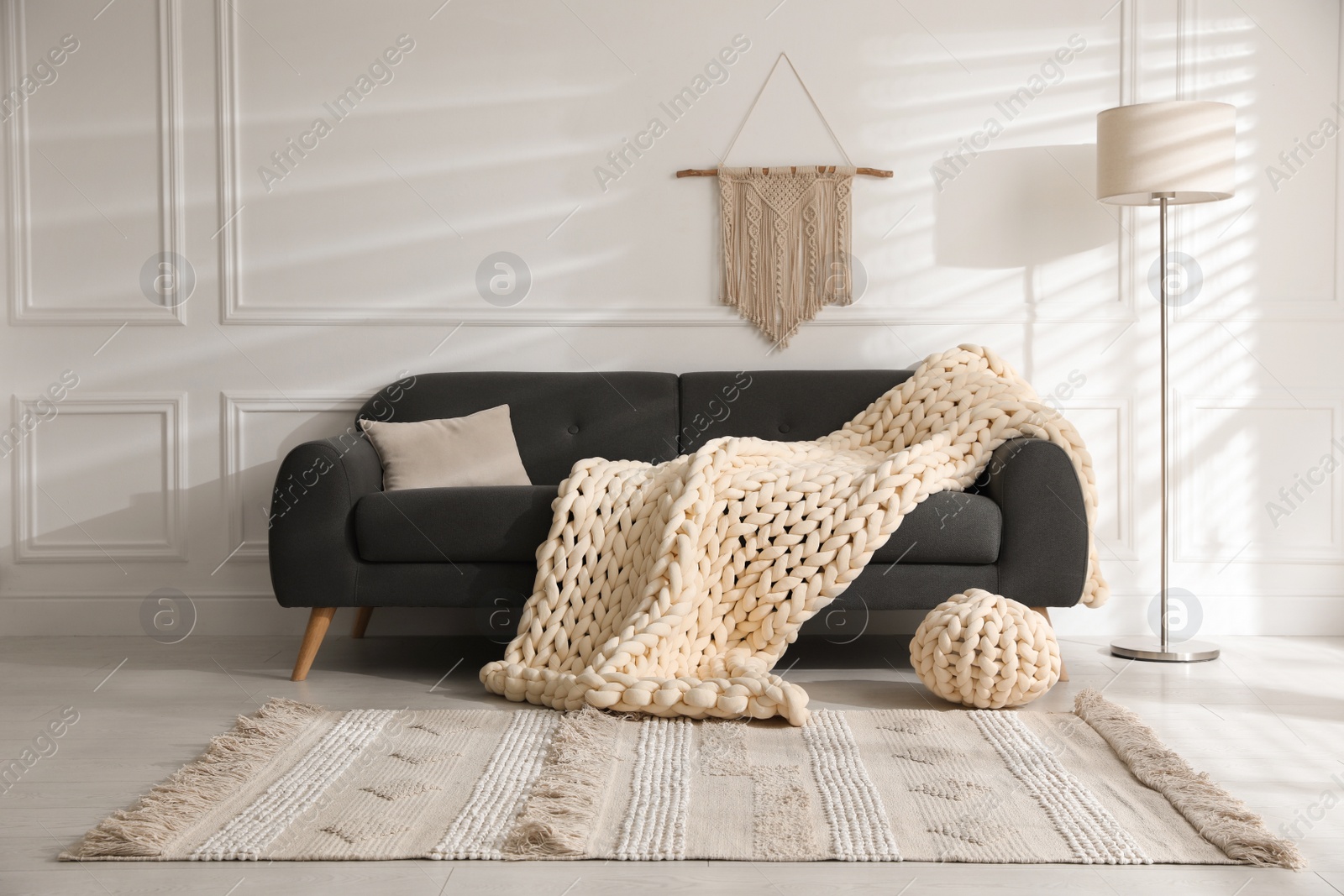 Photo of Soft chunky knit blanket on sofa in living room. Interior design