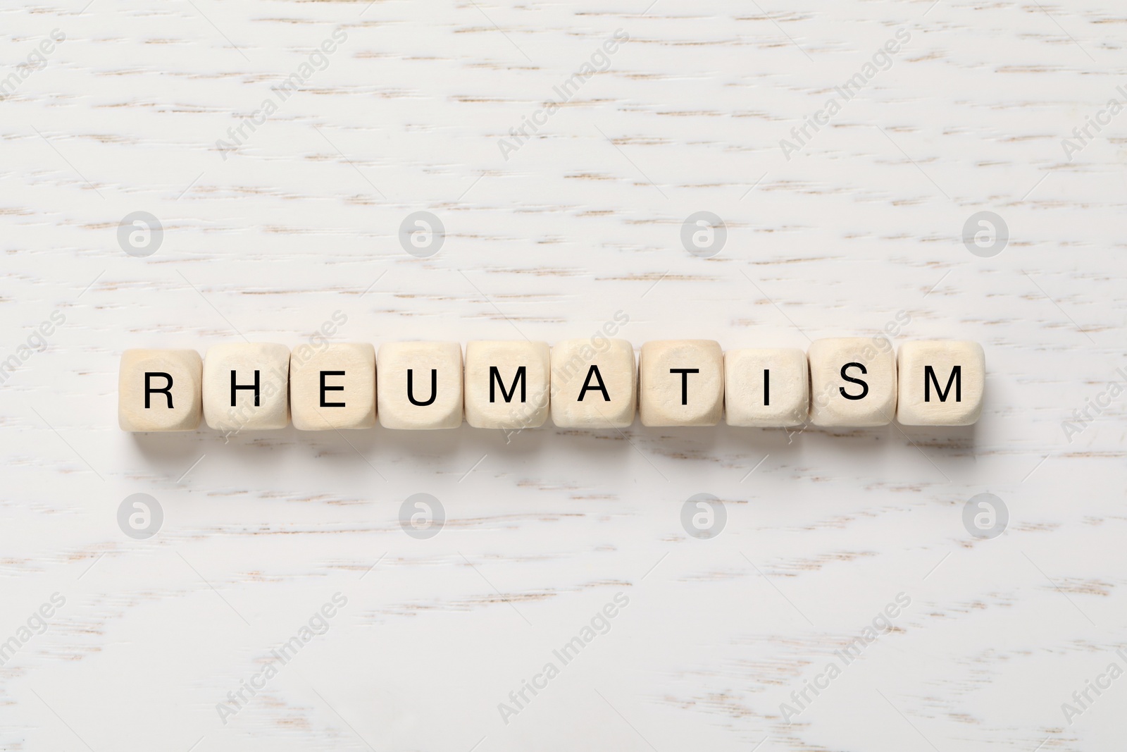 Photo of Cubes with word Rheumatism on white wooden table, flat lay