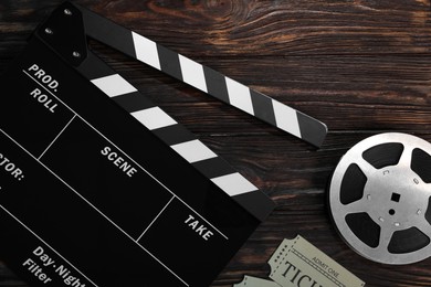 Photo of Clapperboard, movie tickets and film reel on wooden table, flat lay