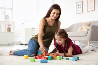 Photo of Young woman and little girl with autistic disorder playing at home