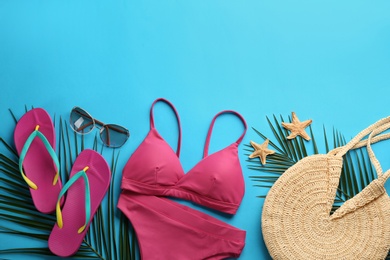 Photo of Beautiful pink bikini and beach accessories on light blue background, flat lay. Space for text