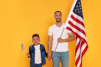 Photo of 4th of July - Independence Day of USA. Happy man and his son with American flags on yellow background
