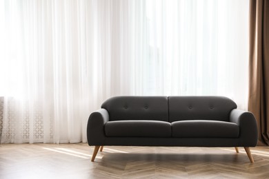 Photo of Comfortable grey sofa near window indoors, space for text. Interior design
