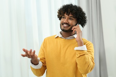 Handsome smiling man taking over smartphone indoors