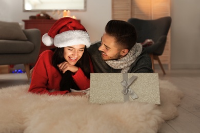 Photo of Young couple with opened Christmas gift box at home