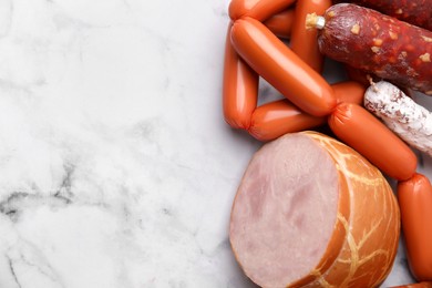 Photo of Different types of sausages on white marble table, above view. Space for text