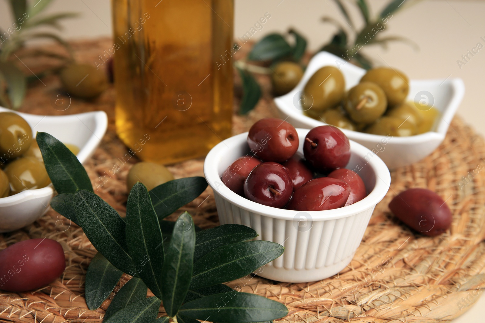 Photo of Bottle of oil, olives and tree twigs on table, closeup