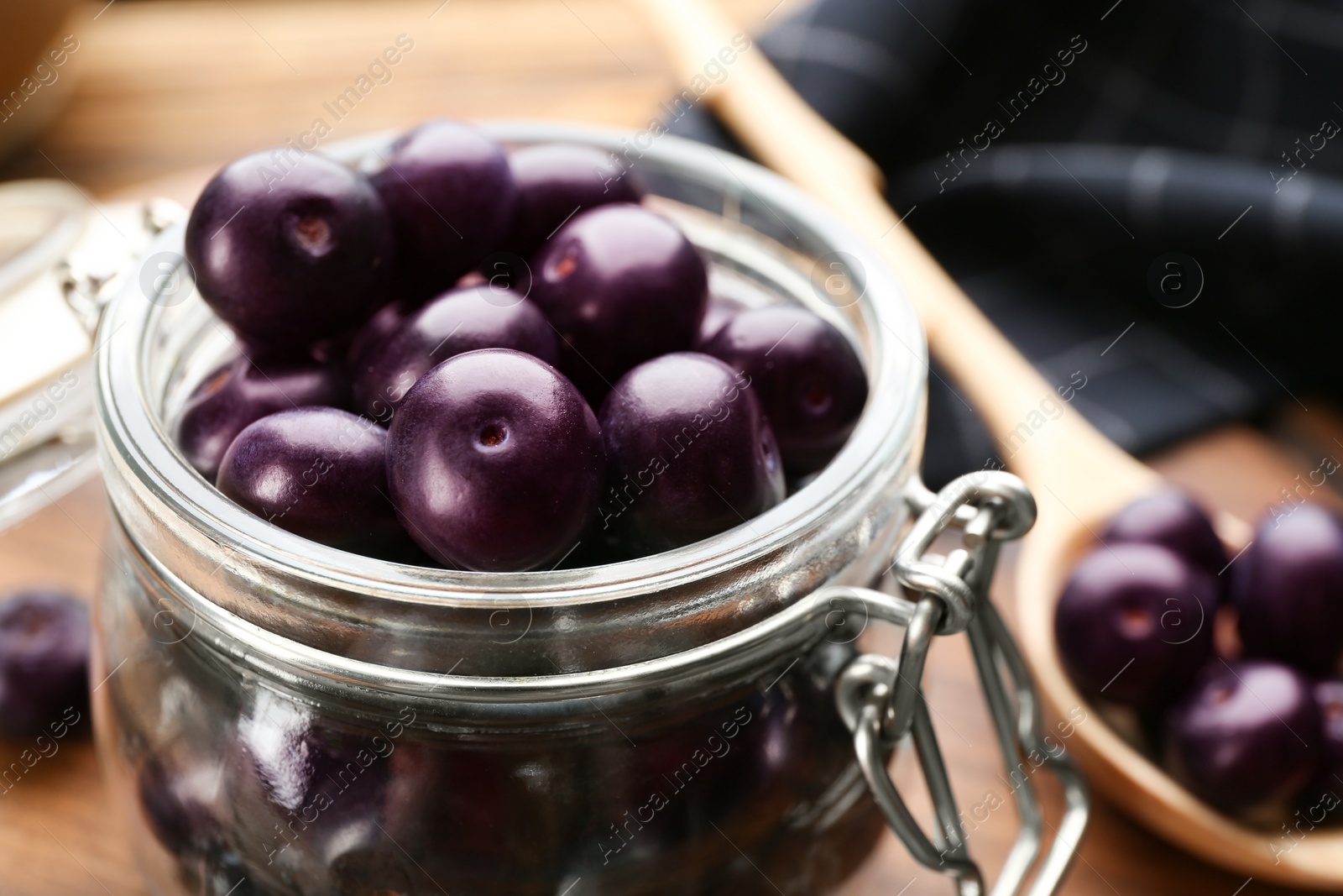 Photo of Jar with fresh acai berries on table, closeup