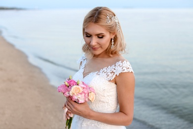 Photo of Happy bride with wedding bouquet on beach