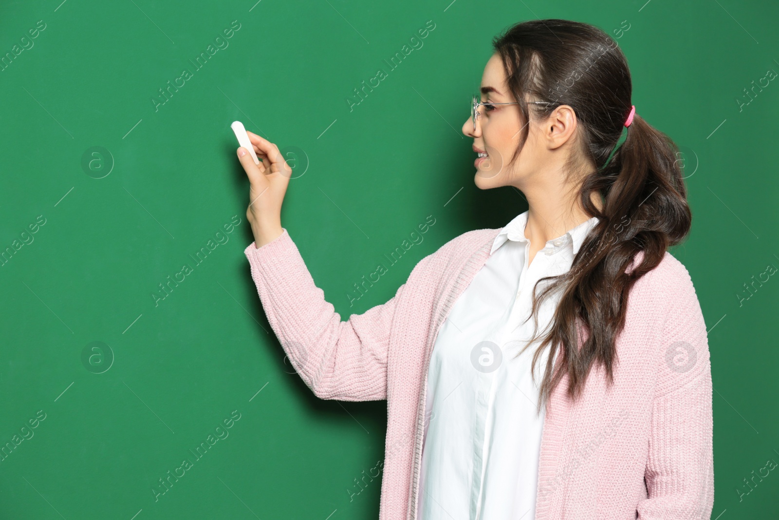 Photo of Portrait of beautiful young teacher writing on chalkboard