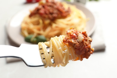 Fork with delicious pasta bolognese over table, closeup