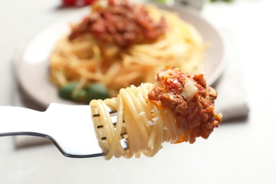 Photo of Fork with delicious pasta bolognese over table, closeup