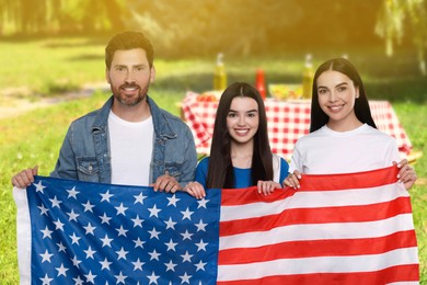 Image of 4th of July - Independence day of America. Happy family with national flag of United States having picnic in park