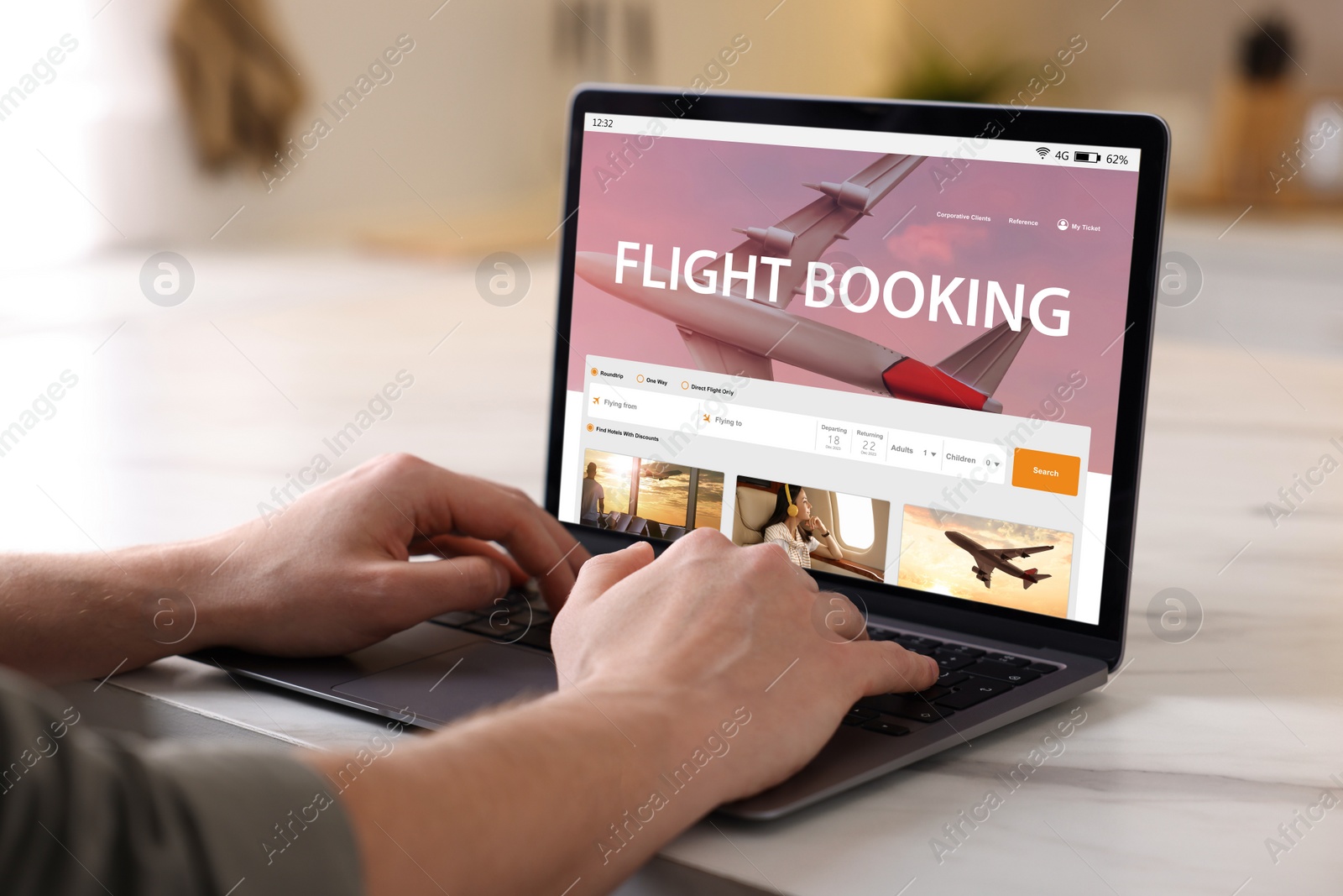 Image of Man using laptop to book flight at white table, closeup