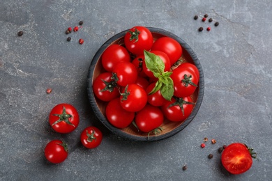 Fresh ripe cherry tomatoes, basil and peppercorns on grey table, flat lay