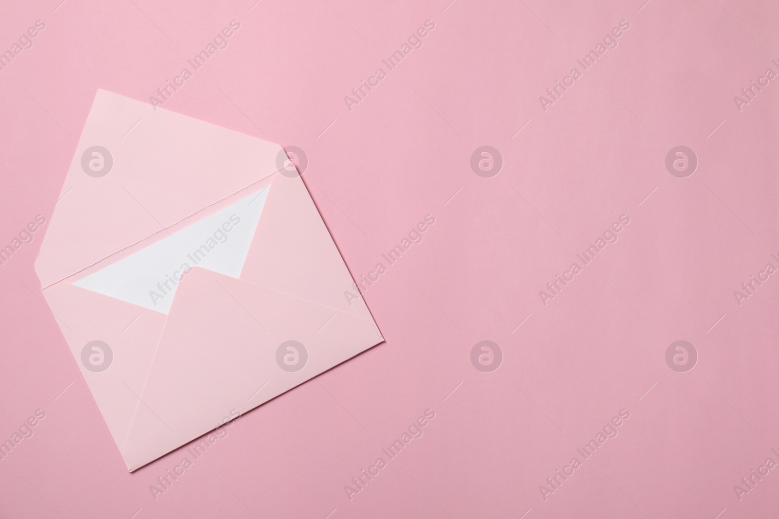 Photo of Letter envelope with card on pink background, top view. Space for text