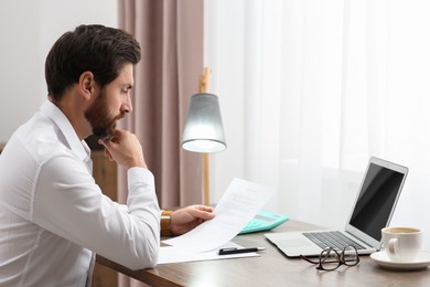 Businessman working with documents at wooden table in office