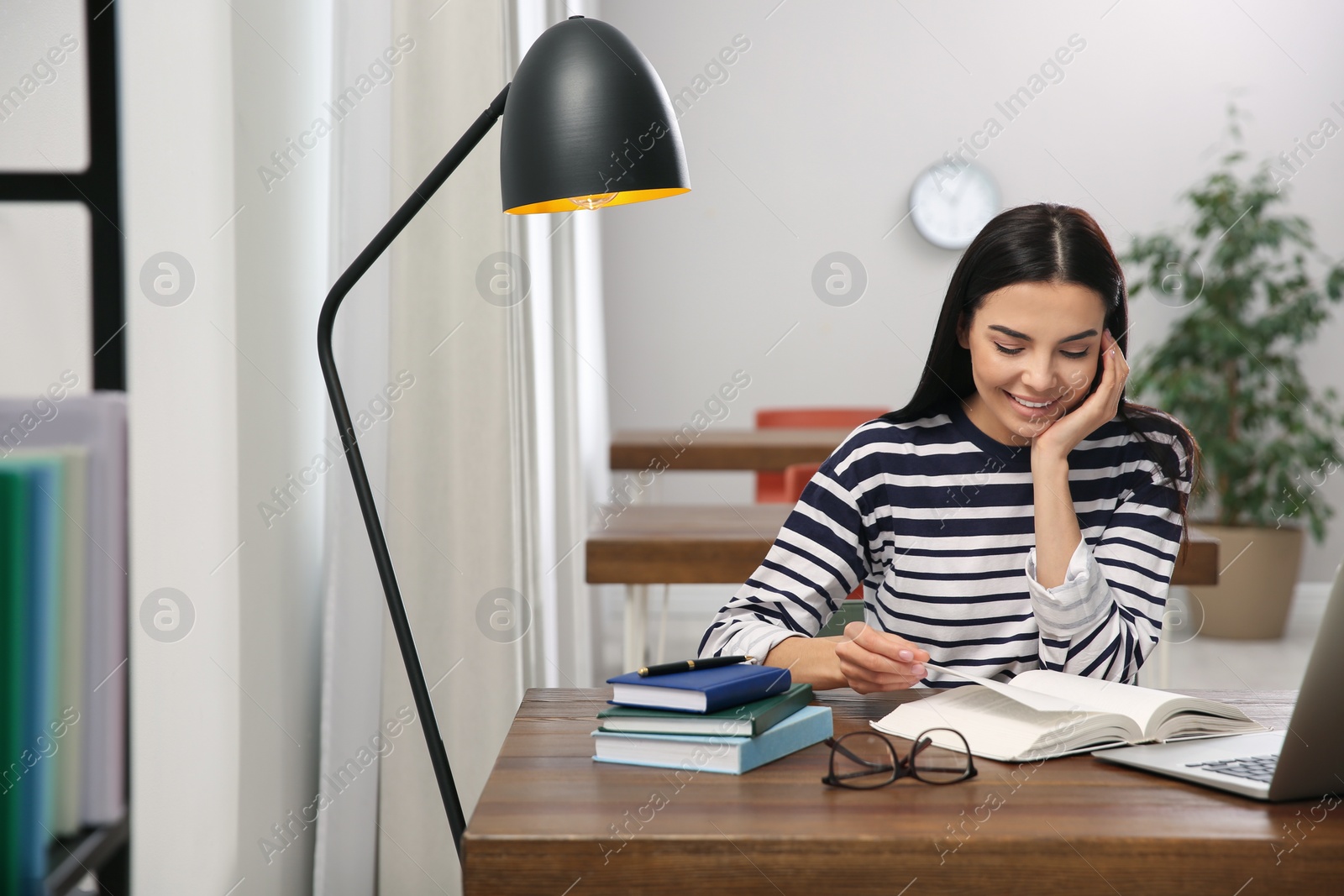 Photo of Young woman reading book at table in library