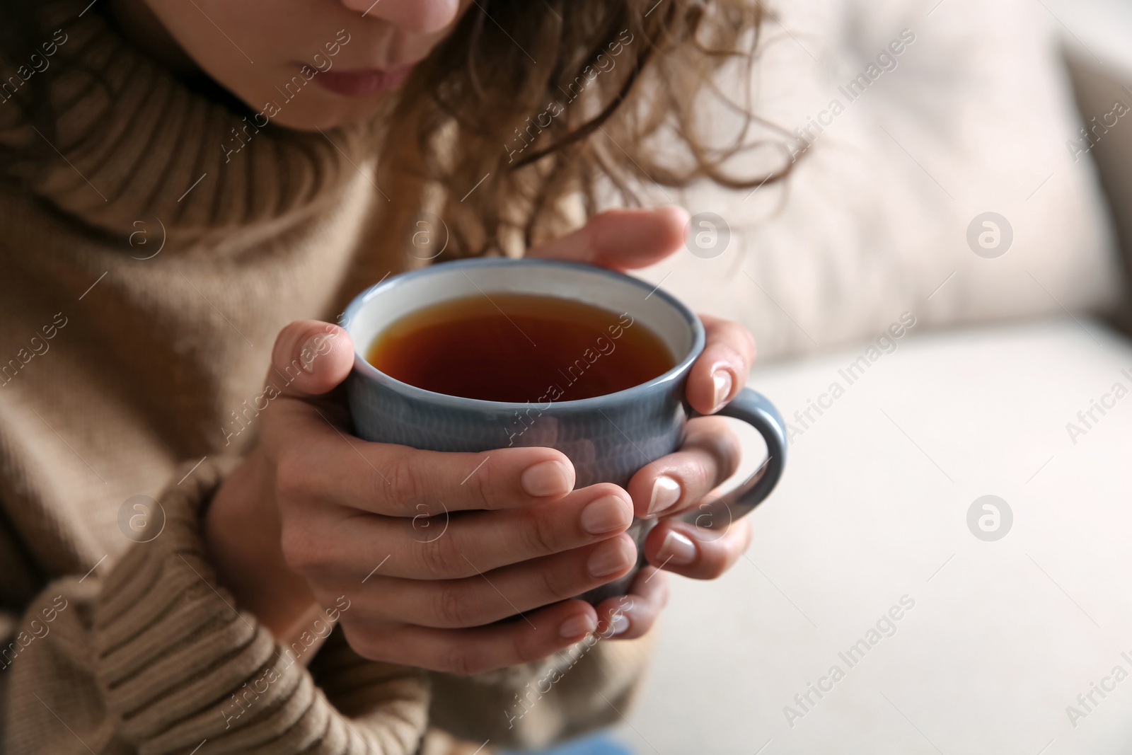 Photo of Woman with cup of hot tea indoors, closeup. Cozy home atmosphere