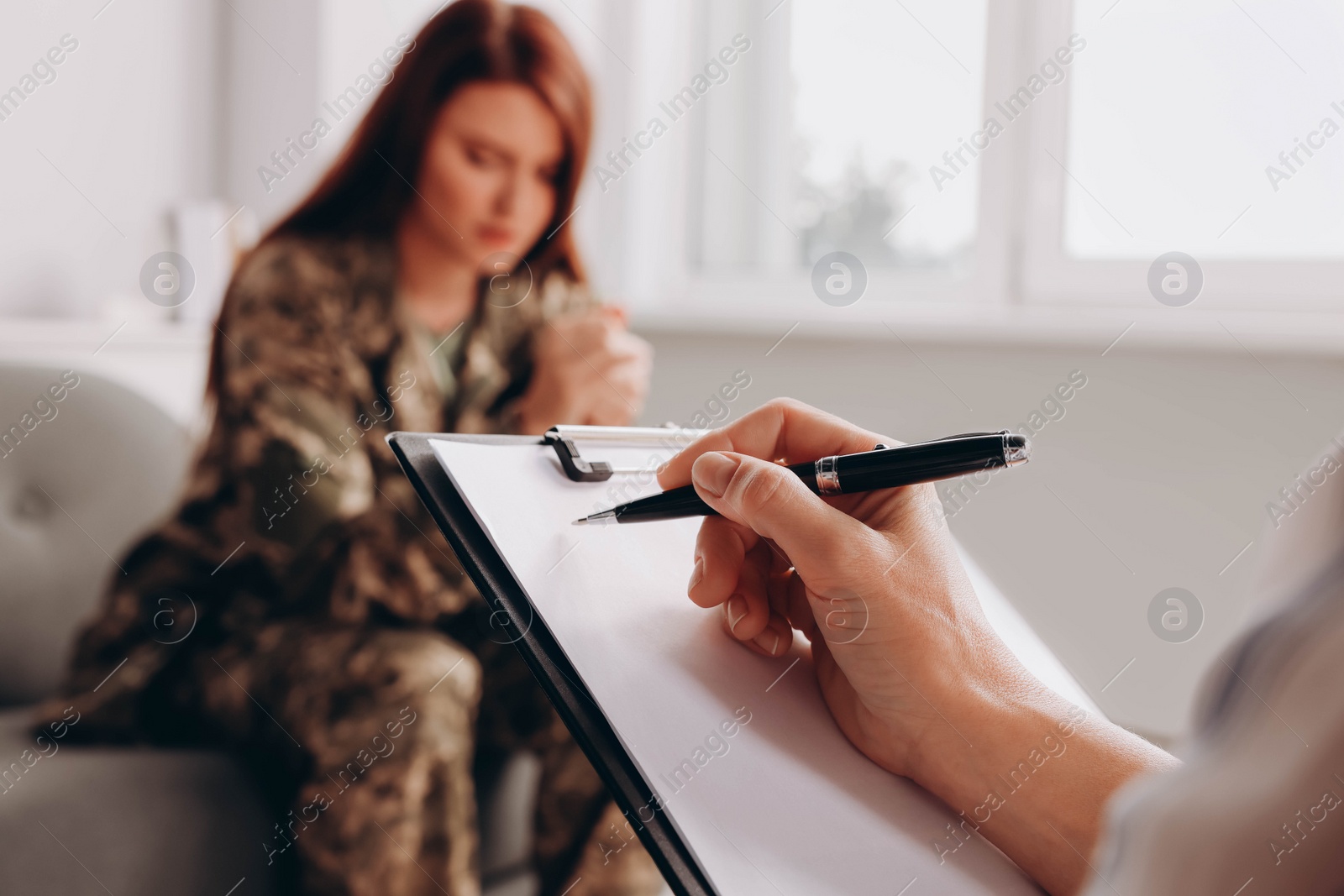 Photo of Psychologist working with military officer in office, focus on hand