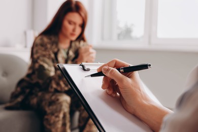 Photo of Psychologist working with military officer in office, focus on hand