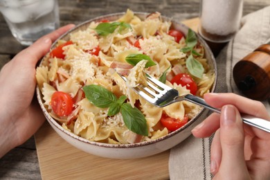 Photo of Woman eating delicious pasta with tomatoes, basil and parmesan cheese at table, closeup
