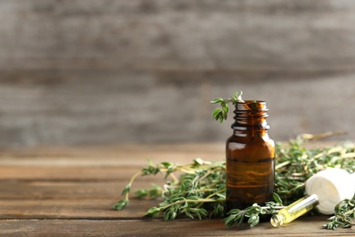 Photo of Bottle of essential oil with thyme on wooden table