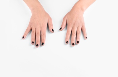 Woman showing black manicure on white background, closeup. Nail polish trends