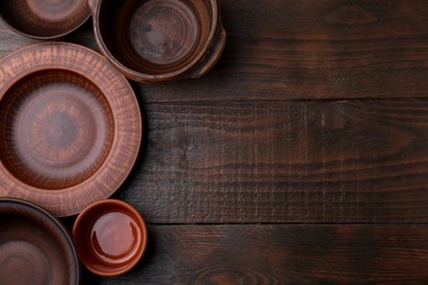 Photo of Set of clay dishes on wooden table, flat lay with space for text. Cooking utensils