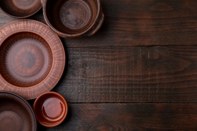 Set of clay dishes on wooden table, flat lay with space for text. Cooking utensils