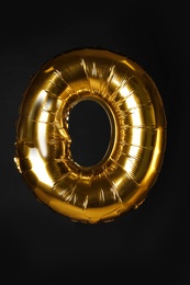 Golden letter O balloon on black background