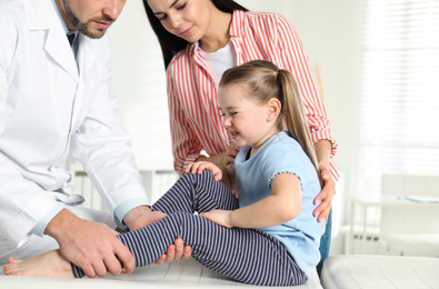 Photo of Professional orthopedist examining little patient's leg in clinic