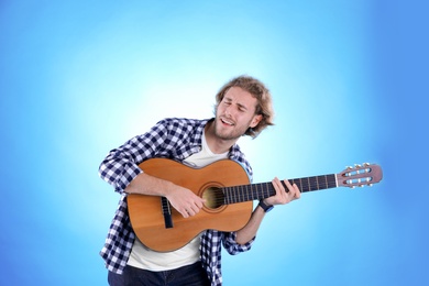 Photo of Young man playing acoustic guitar on color background