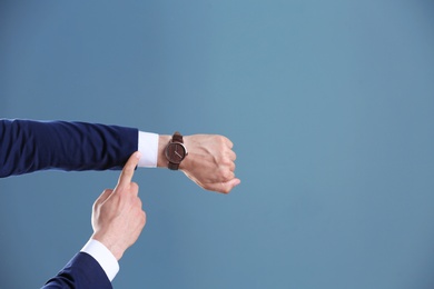 Businessman with wristwatch on color background. Time concept