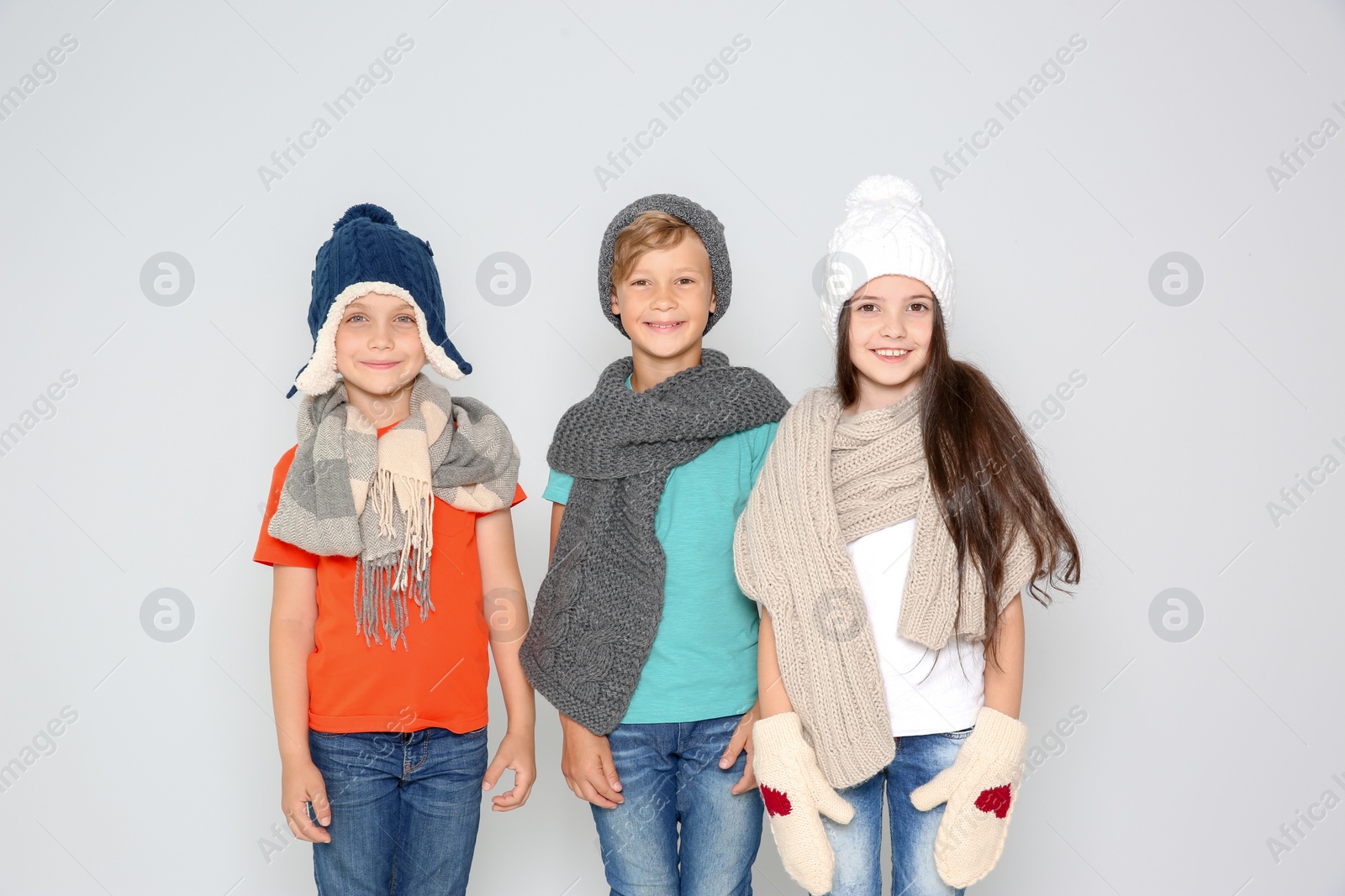 Photo of Cute little children in warm clothes posing on light background. Christmas celebration