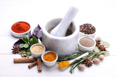 Photo of Mortar with pestle and different spices on white wooden table