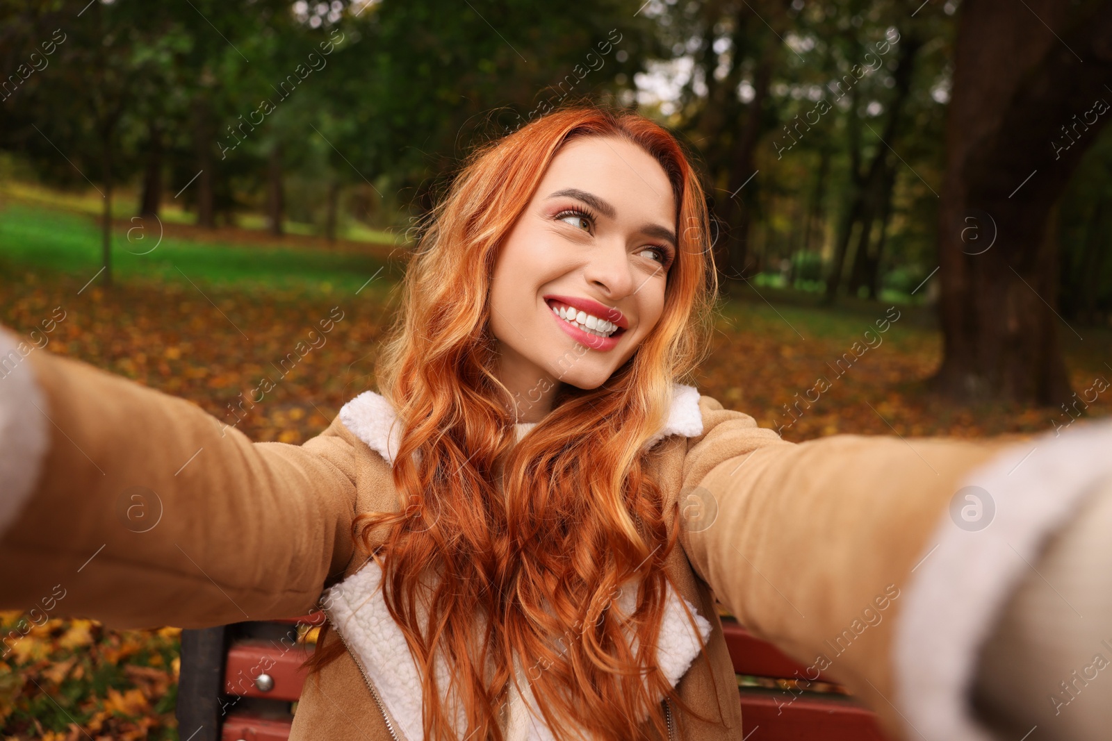 Photo of Portrait of happy woman taking selfie in autumn park