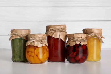 Photo of Jars with canned fruit jams on light grey table