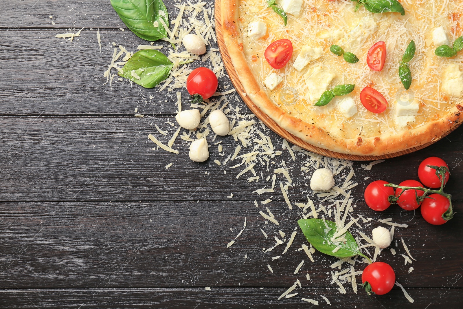 Photo of Delicious pizza with cheese, basil and tomatoes on wooden table, top view
