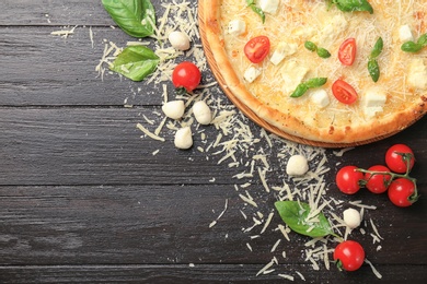 Delicious pizza with cheese, basil and tomatoes on wooden table, top view