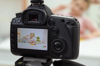 Cute little blogger with slime recording video at home, focus on camera