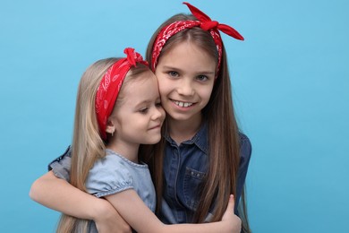 Cute little sisters on light blue background