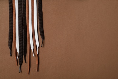 Photo of Different shoelaces on brown background, flat lay. Space for text