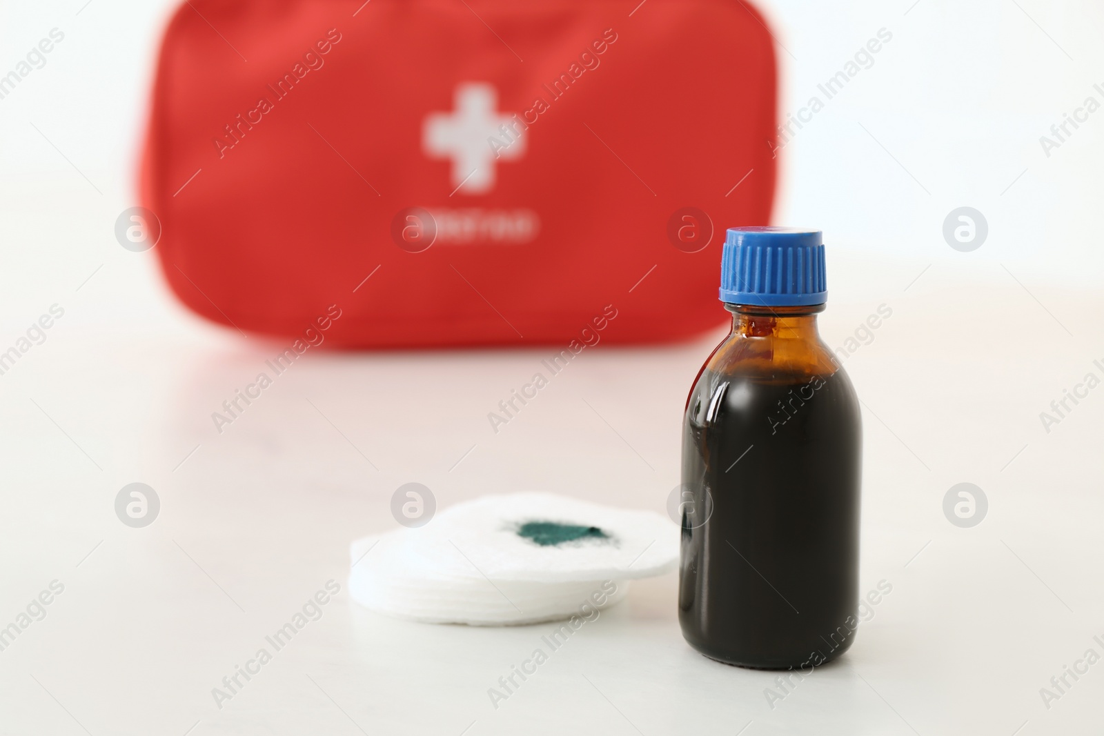 Photo of Bottle of brilliant green and cotton pads on white table