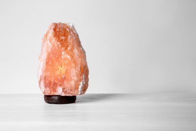 Himalayan salt lamp on table against light background